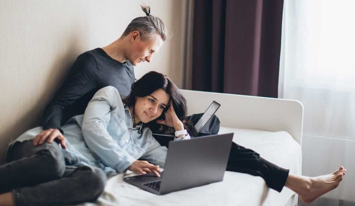 couple looking for personal loans on their computer in bedroom