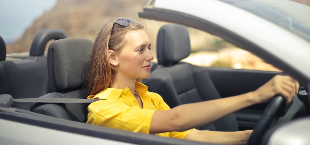 young woman in yellow top driving car